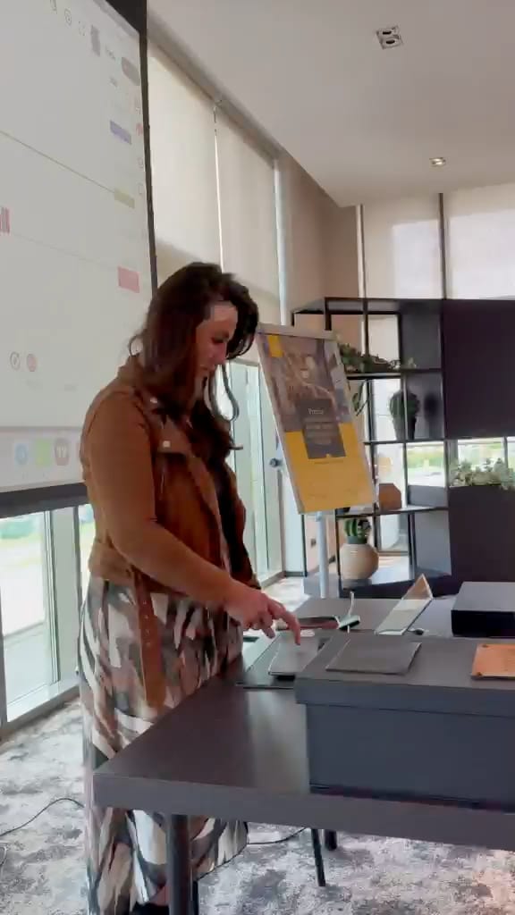 Short clip from the room: the presenter at the laptop beside the event standee.